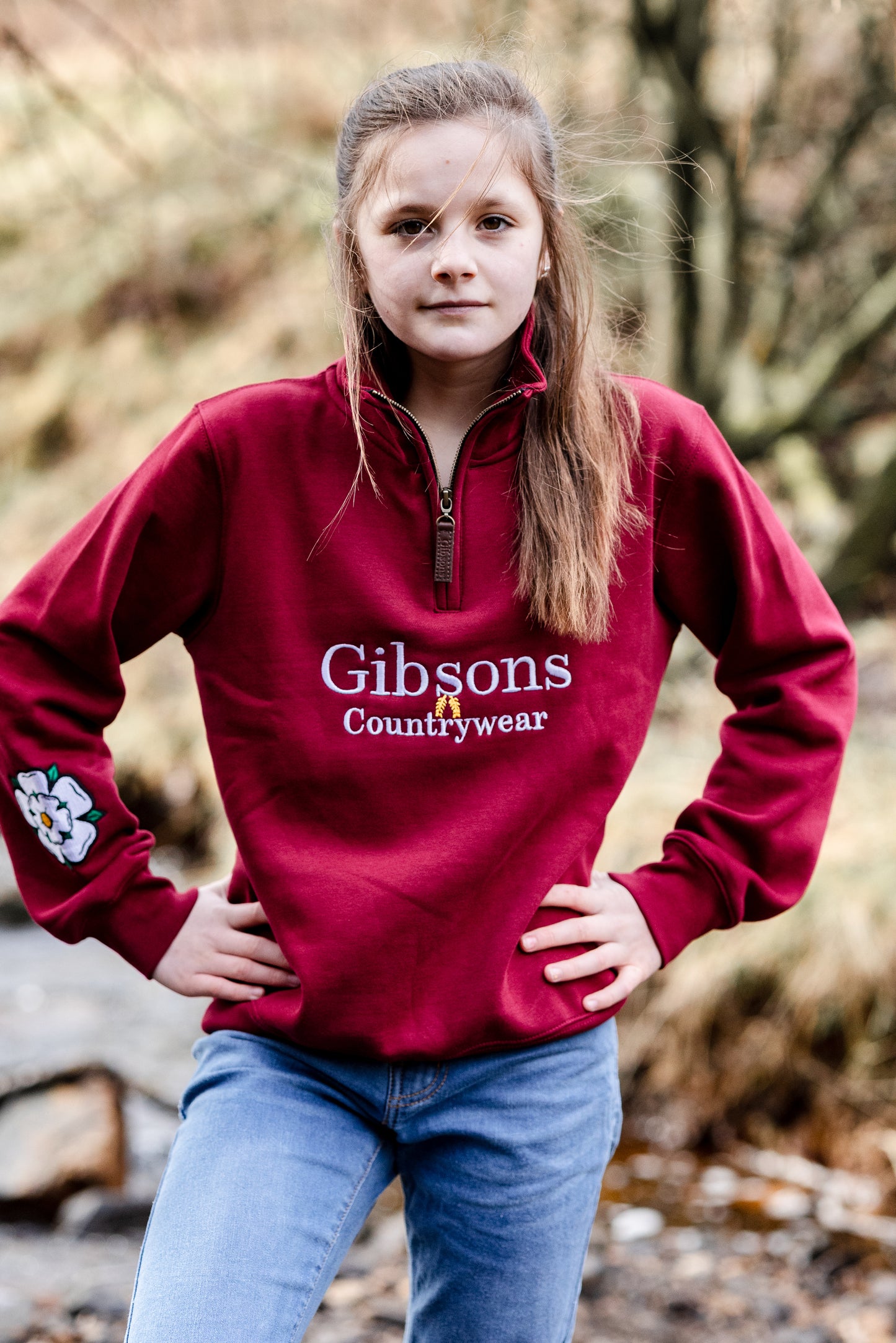 Girl wearing a red 'Gibsons Countrywear' sweatshirt in a natural setting