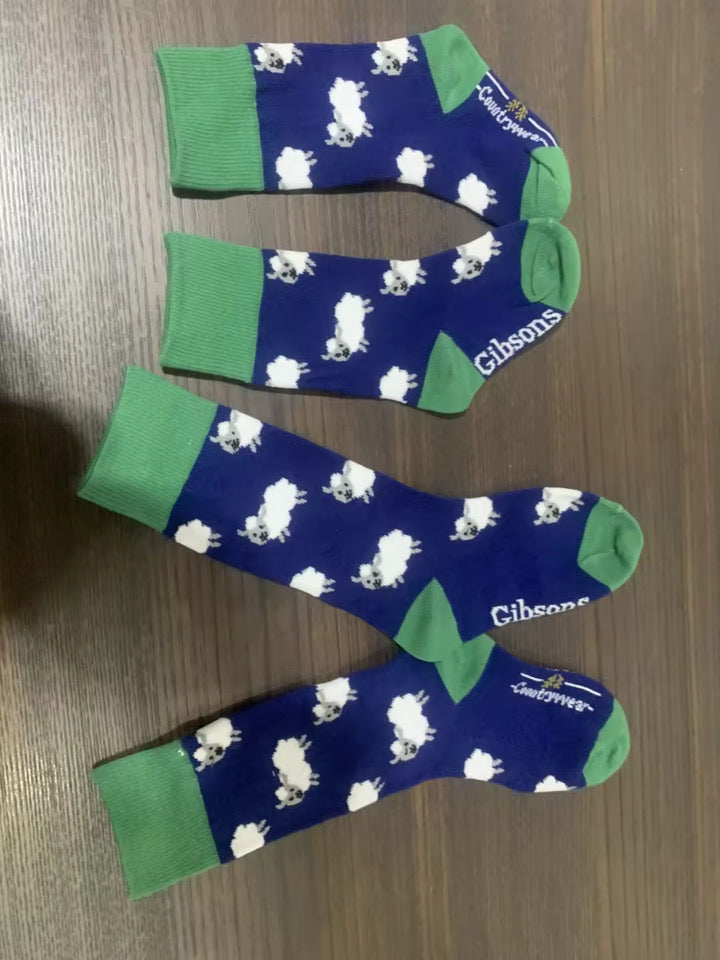 Two pairs of socks with sheep pattern on a wooden surface