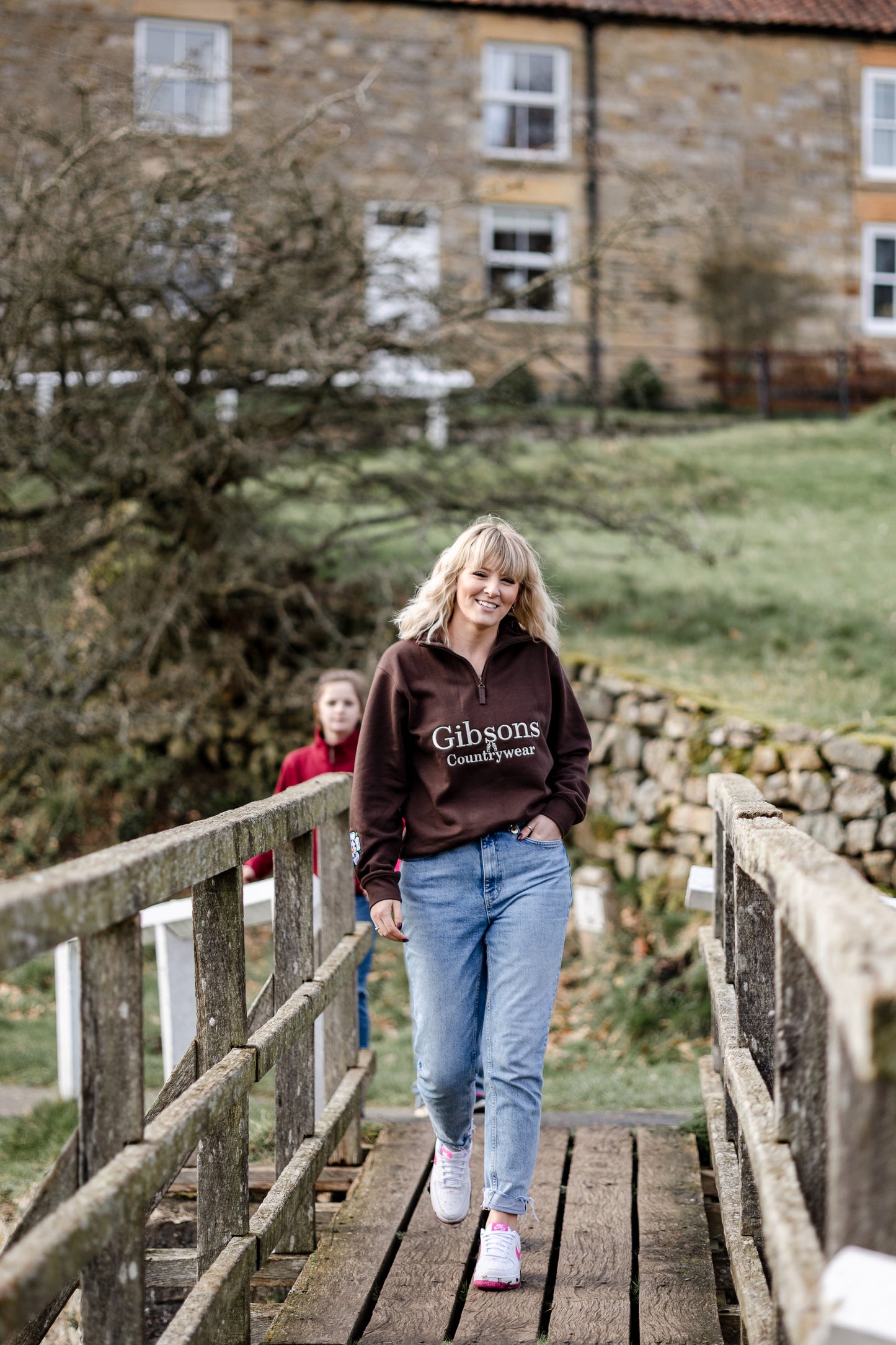 Woman walking on a wooden bridge with a stone building in the background