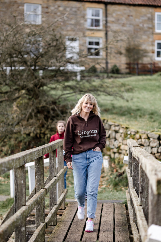 Woman walking on a wooden bridge with a stone building in the background