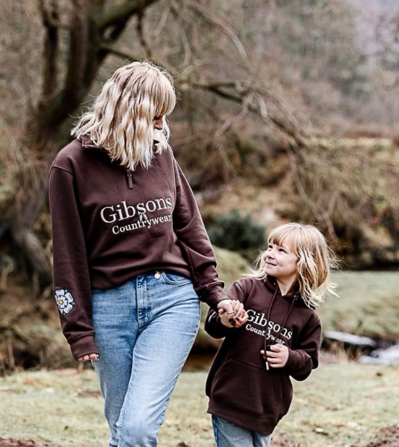 Two people wearing brown 'Gibsons Countrywear' sweatshirts walking outdoors.