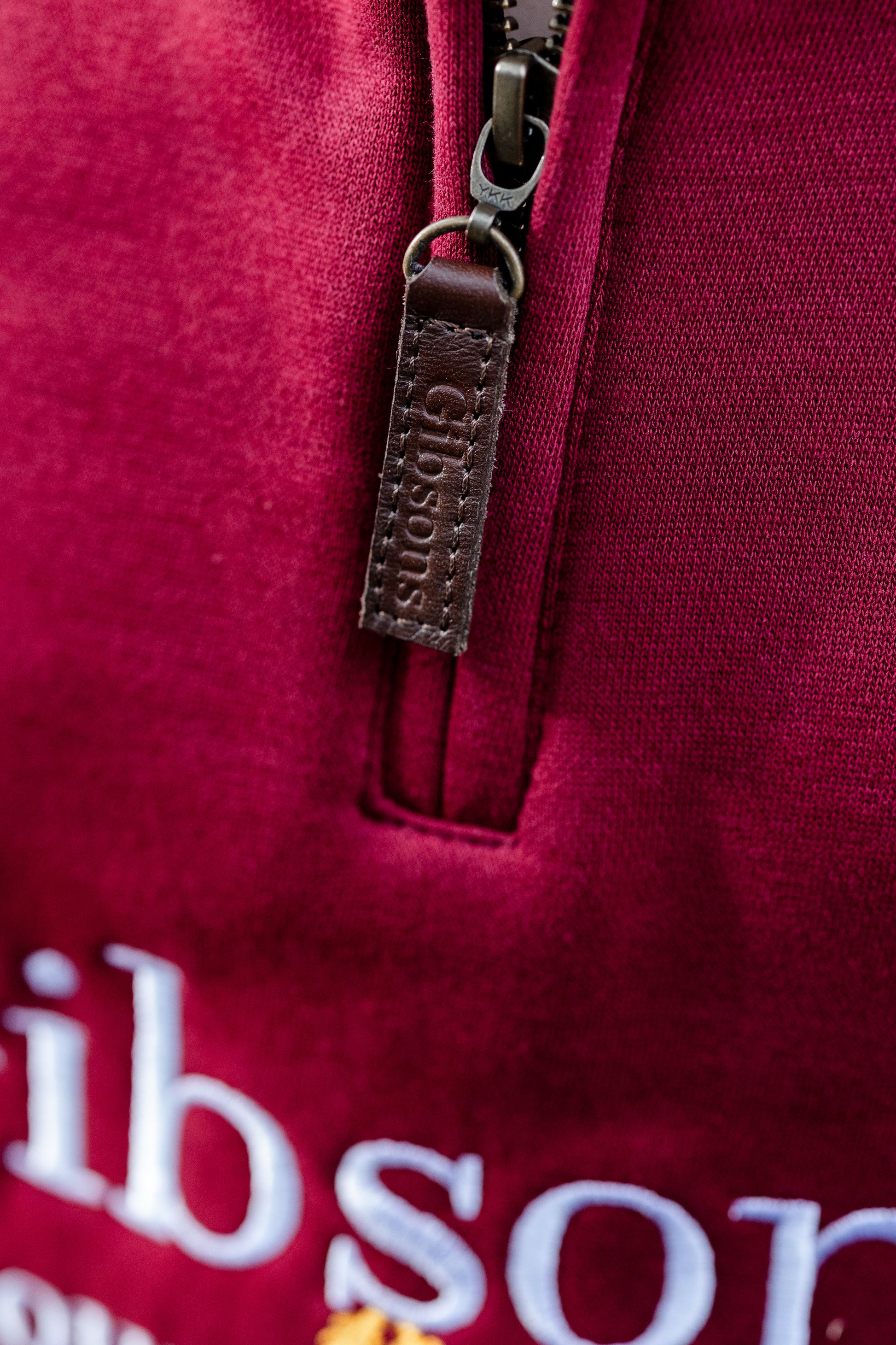 Close-up of a red hoodie with a zipper and visible branding.