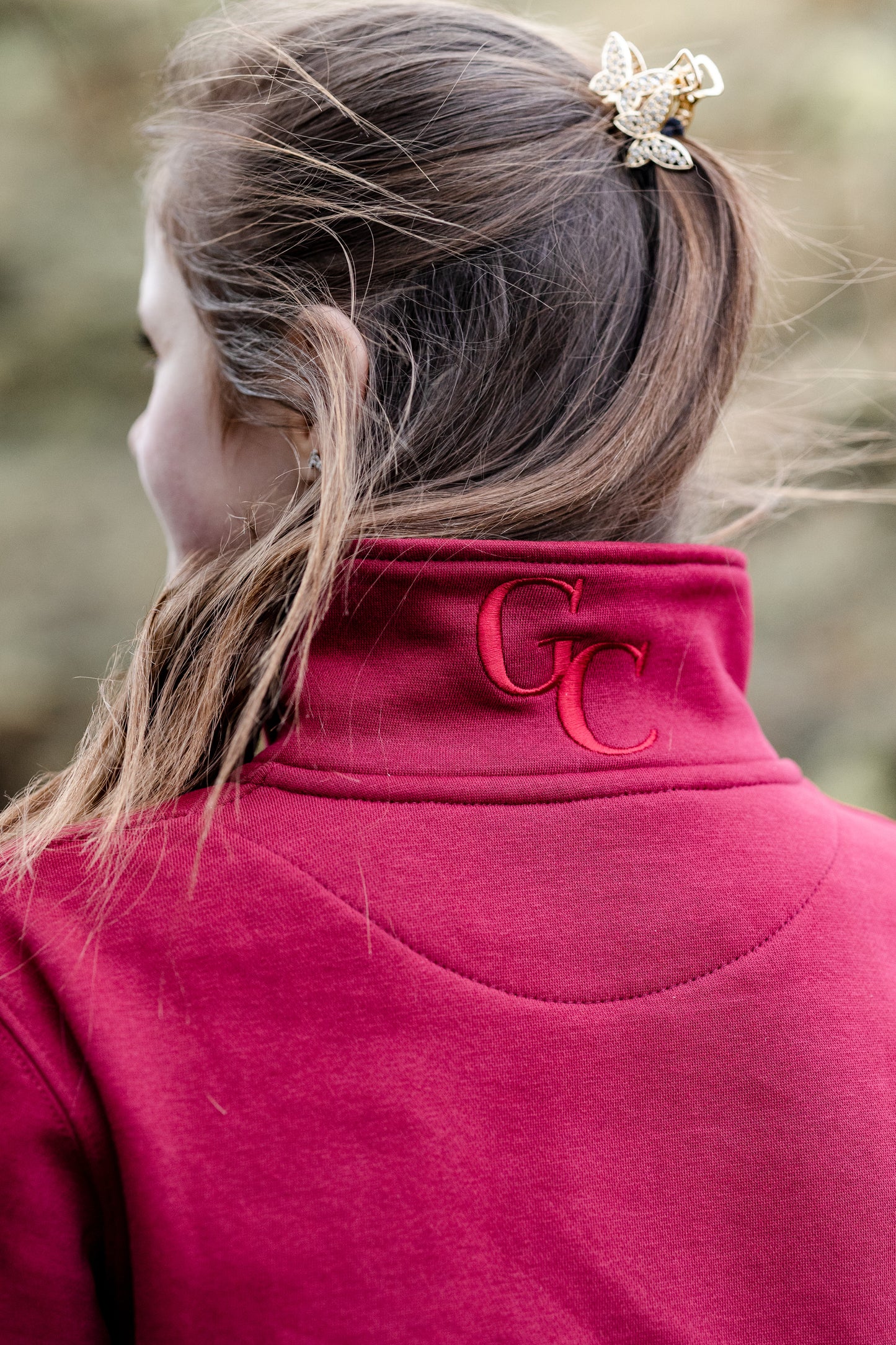Person wearing a red jacket with a logo, focusing on the collar area.