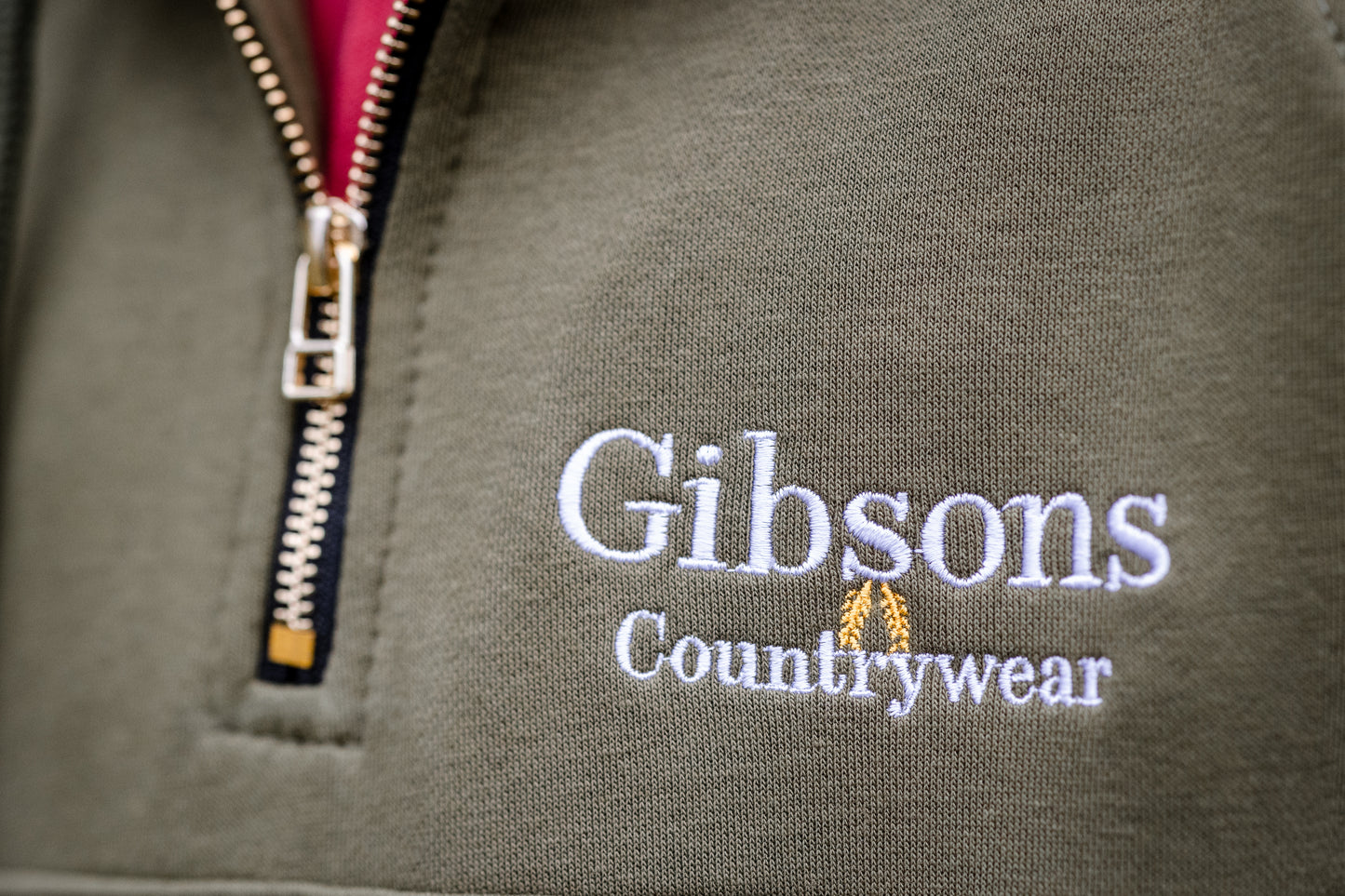 Gibsons Countrywear logo on a green jacket with a zipper.