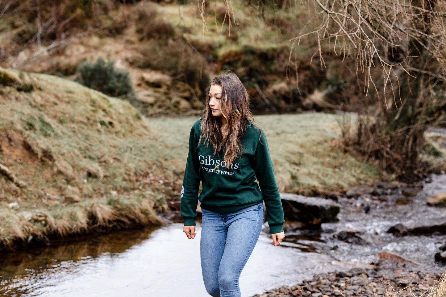Maddy walking near a stream wearing brand new green sweatshirt from Gibson’s country wear 