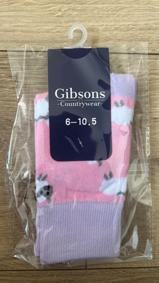 Pink floral sock with 'Gibsons Countrywear' label on a clear plastic bag against a wooden surface.