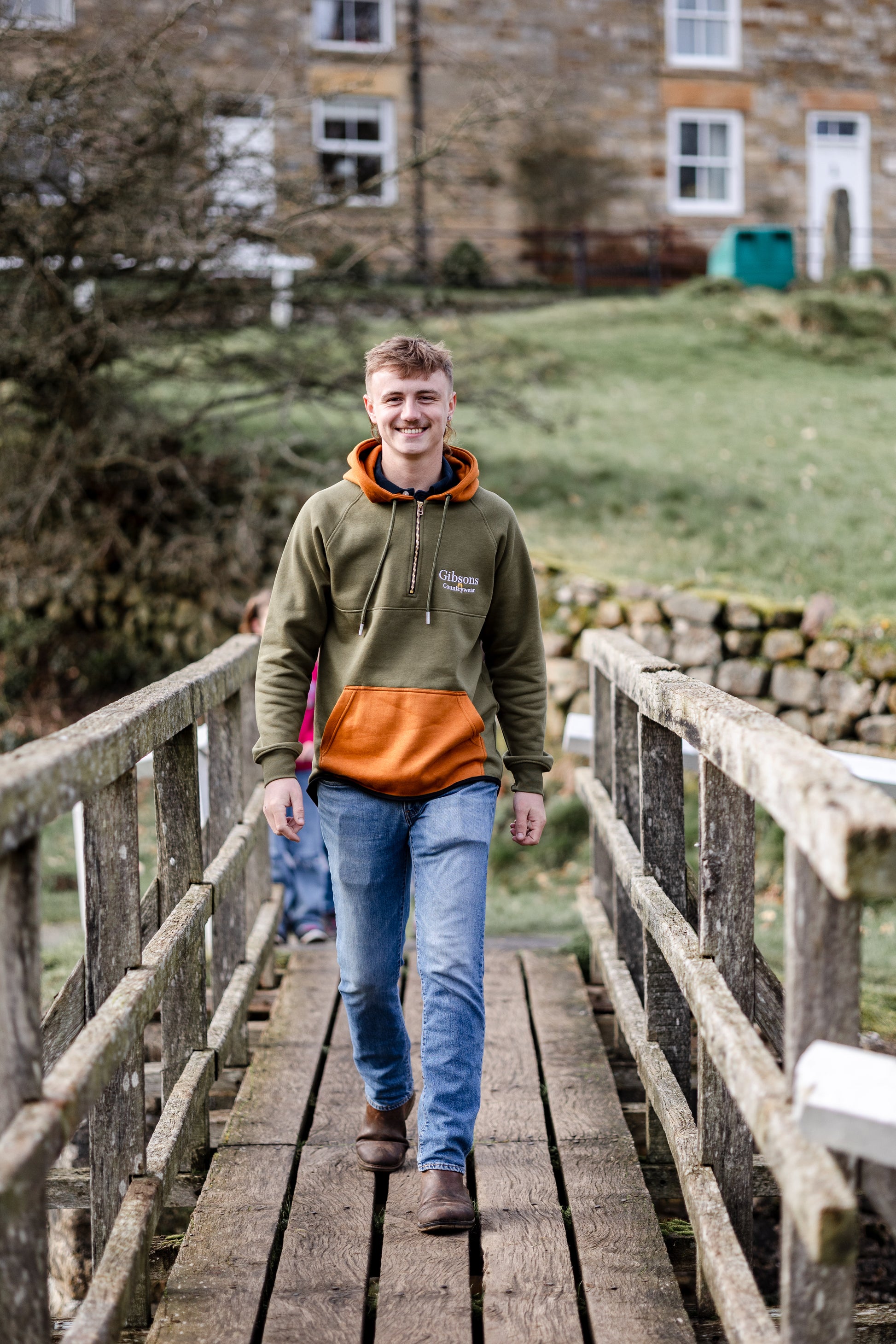 Man walking on a wooden bridge with a building in the background