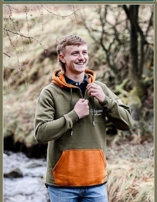 Man wearing a green and brown hoodie in a forest setting