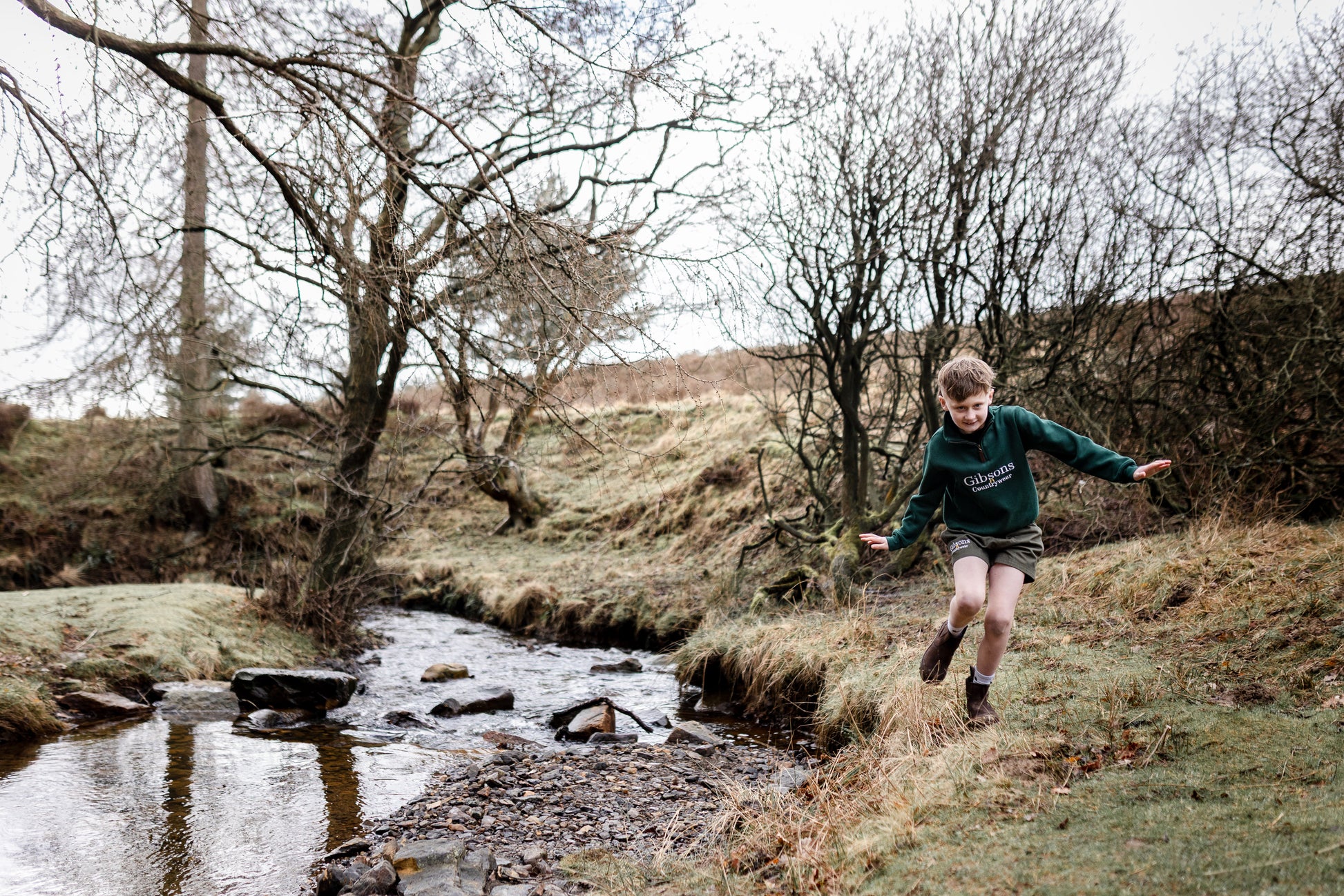 Child running by a stream in a natural landscape