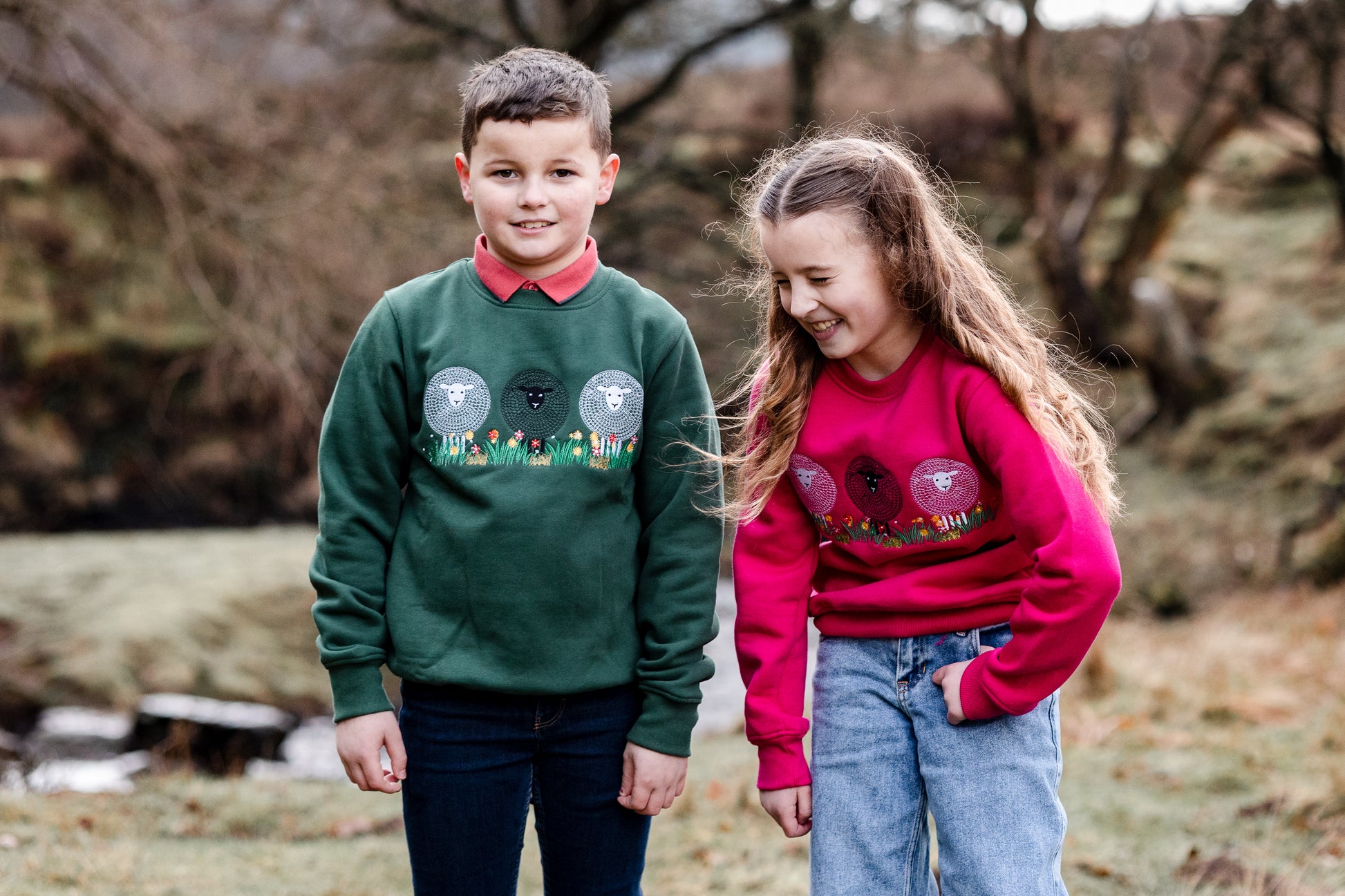 Two children wearing sweaters with animal designs outdoors.