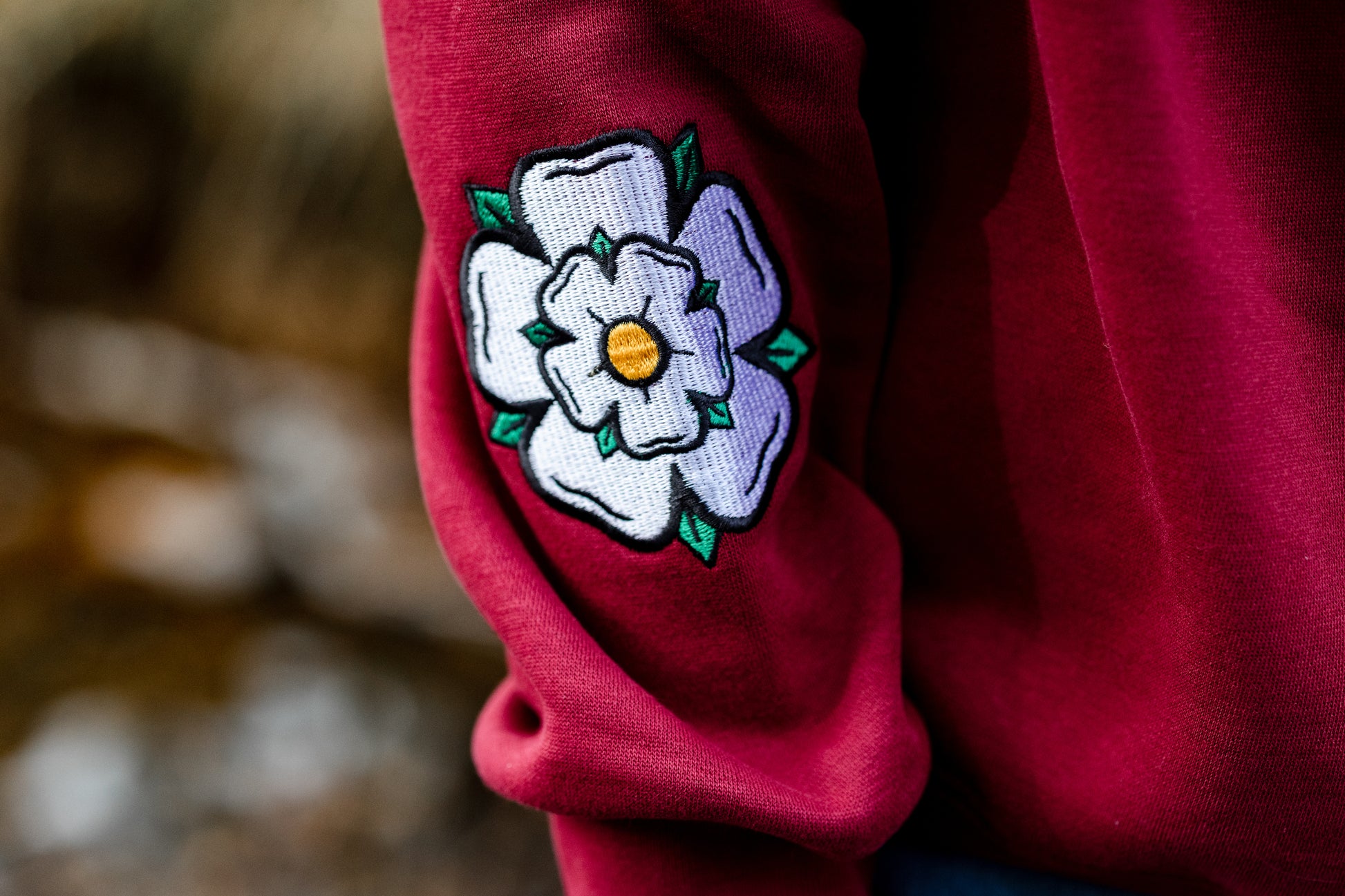 Red garment with a white Yorkshire rose on a blurred natural background